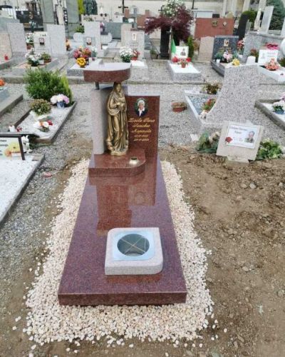 Lapide funeraria in granito rosso con statua religiosa in cimitero - Onoranze Funebri Musocco Milano