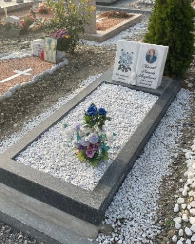 Lapide funeraria in marmo bianco con bordo nero e composizione floreale - Onoranze Funebri Musocco Milano