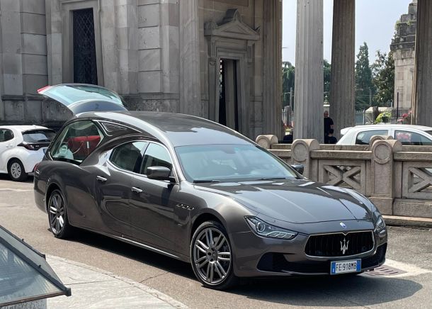 Moderna auto funebre Maserati nera, parcheggiata sul piazzale del cimitero Maggiore durante un funerale curato da onoranze funebri Musocco - Milano
