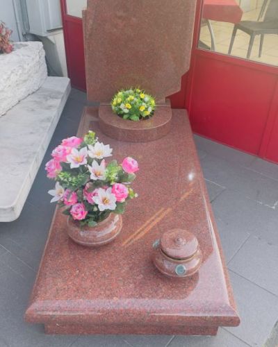 Lapide funeraria in granito rosso con composizione floreale - Onoranze Funebri Musocco Milano