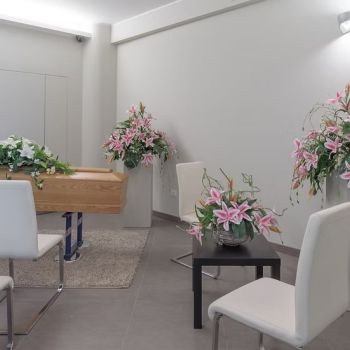 feretro in casa del commiato con sedie e addobbi floreali di onoranze funebri Musocco Milano